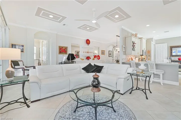 Living area with arched walkways, a ceiling fan, ornamental molding, light tile patterned floors, and recessed lighting