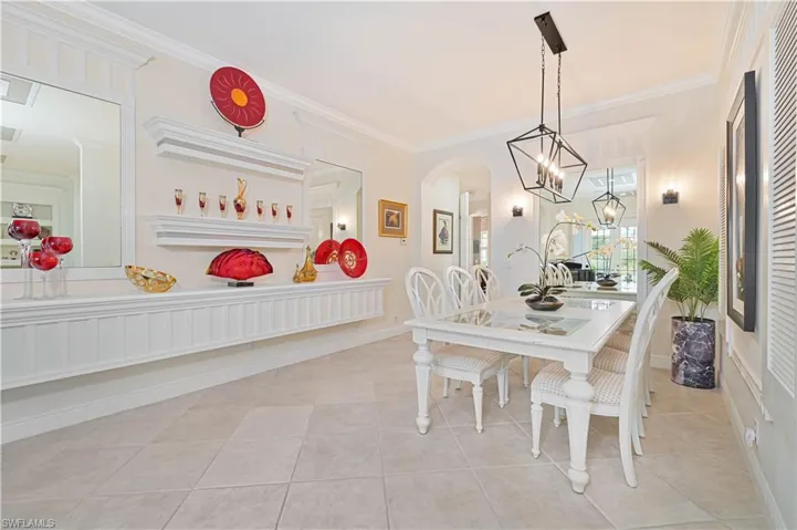 Dining space featuring arched walkways, ornamental molding, light tile patterned floors, and a chandelier