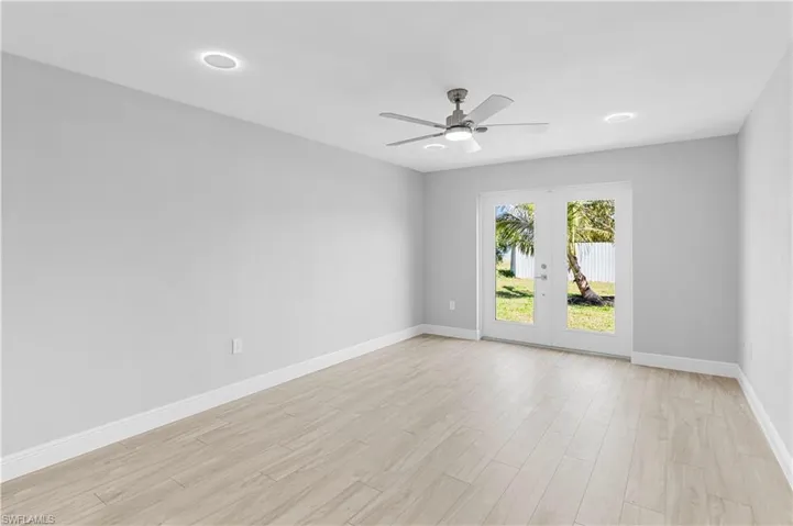 Unfurnished room featuring ceiling fan, light hardwood / wood-style floors, and french doors