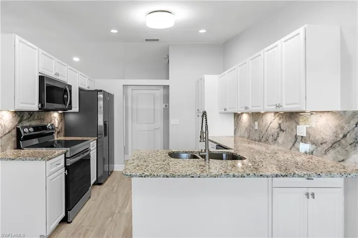 Kitchen with white cabinetry, stainless steel appliances, and kitchen peninsula