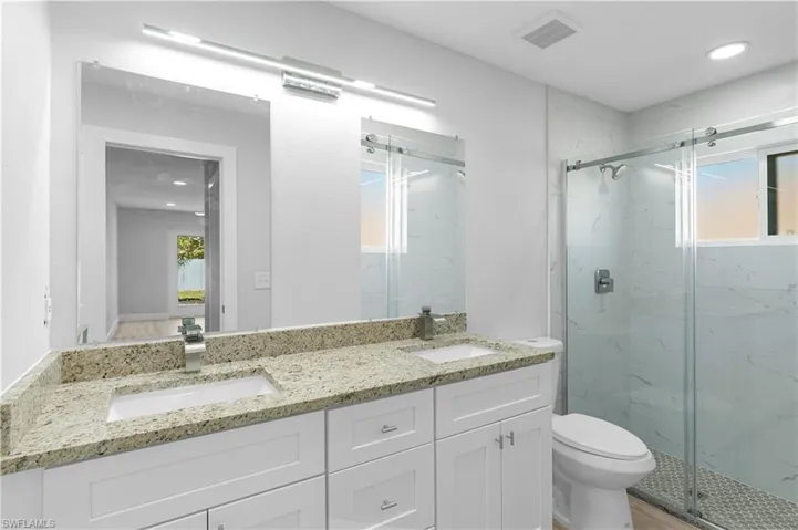 Bathroom with an enclosed shower, vanity, and toilet