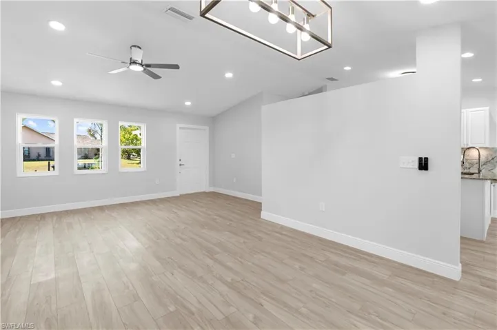 Unfurnished living room with sink, vaulted ceiling, ceiling fan, and light wood-type flooring