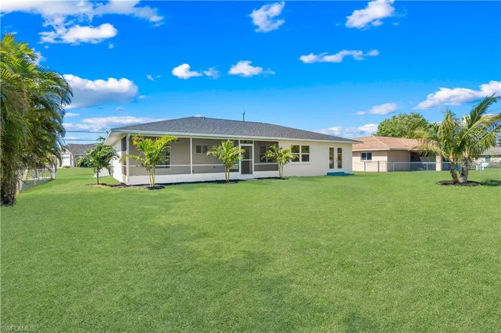 Rear view of property with a sunroom and a lawn