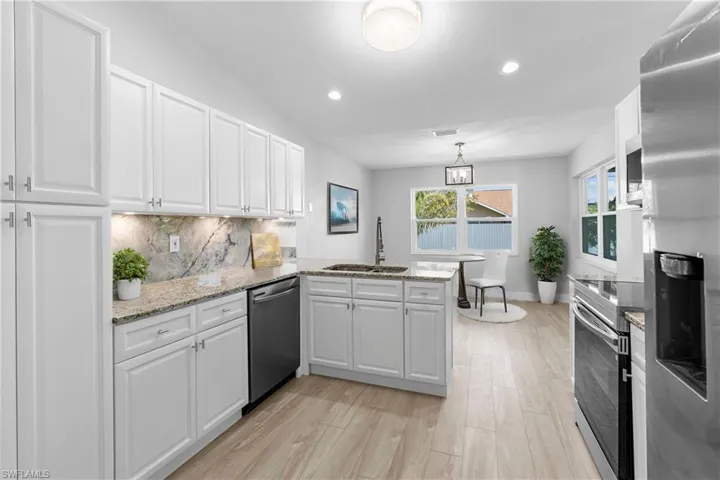 Kitchen with sink, white cabinetry, backsplash, stainless steel appliances, and kitchen peninsula
