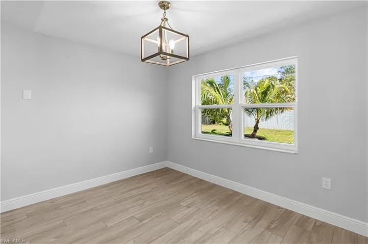 Spare room with a chandelier and light wood-type flooring