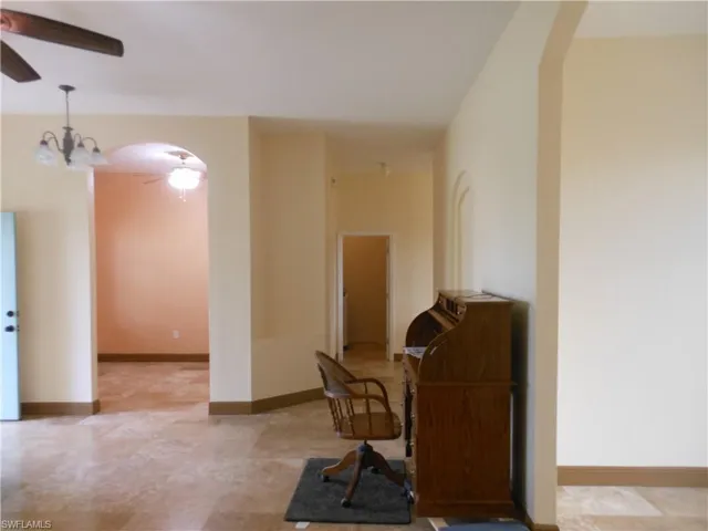 Home office featuring arched walkways, ceiling fan, and a chandelier