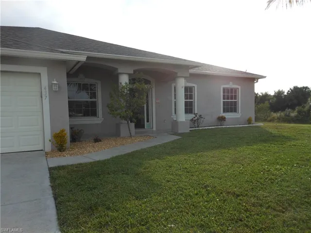 View of front of home with a shingled roof, a front yard, stucco siding, and an attached garage