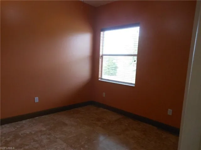 Spare room featuring baseboards and dark floors