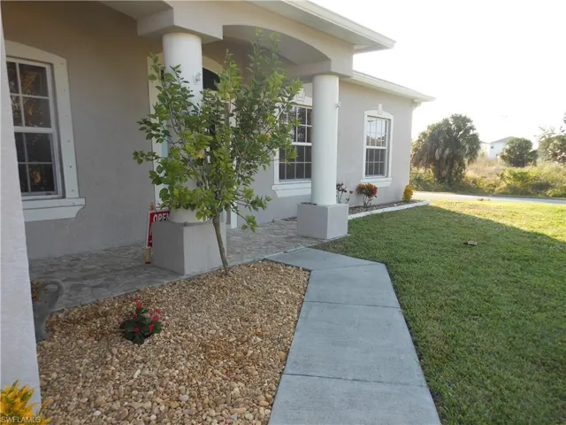 Doorway to property featuring a yard, stucco siding, and covered porch