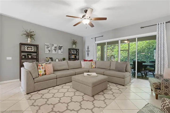 Spacious room featuring tile flooring, ceiling fan, and large sliding glass doors opening to an outdoor patio with screening