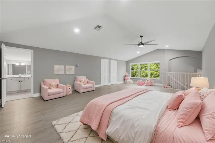 Spacious room featuring vaulted ceilings, light wood-finish flooring, a contemporary ceiling fan, and recessed lighting