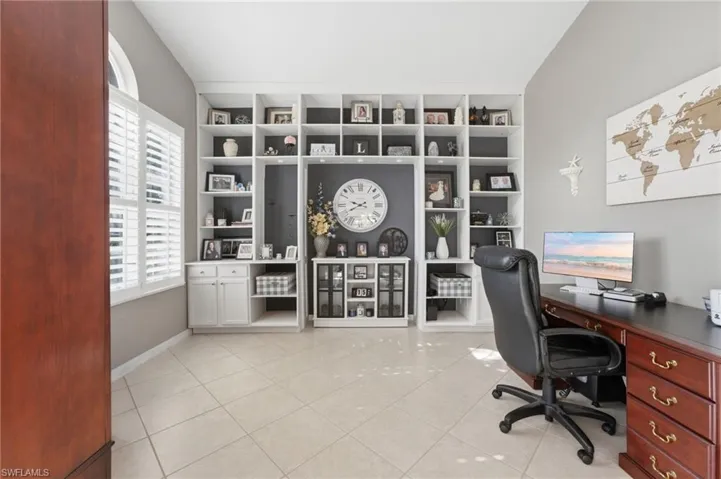 Custom built-in shelving with integrated cabinetry, plantation shutters, tiled flooring, and a high ceiling