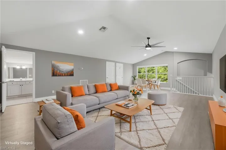 *VIRTUALLY STAGED* Expansive living area with vaulted ceilings and light wood-finish flooring