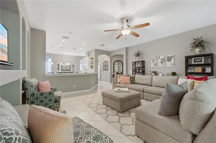 Spacious living area featuring tile flooring, a ceiling fan, recessed lighting, and a built-in wall niche with arched accents
