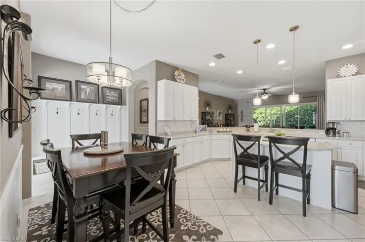 Open-concept kitchen and dining area featuring white cabinetry, light-toned countertops, and tile flooring