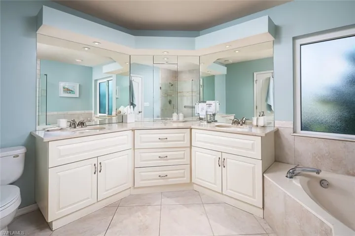 Full bathroom with a sink, a bath, toilet, a stall shower, and double vanity