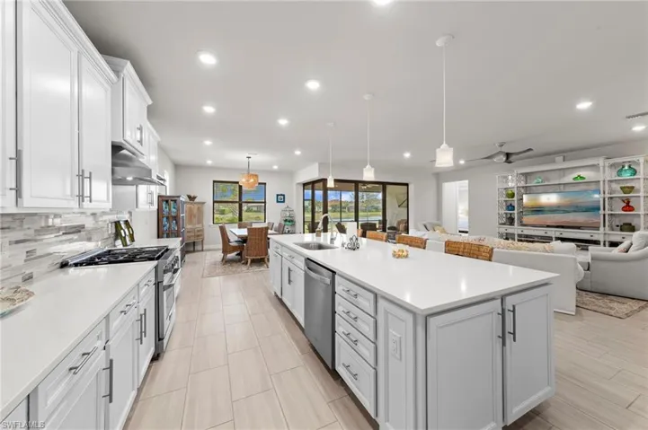 Kitchen with white cabinets, open floor plan, pendant lighting, stainless steel appliances, and a spacious island