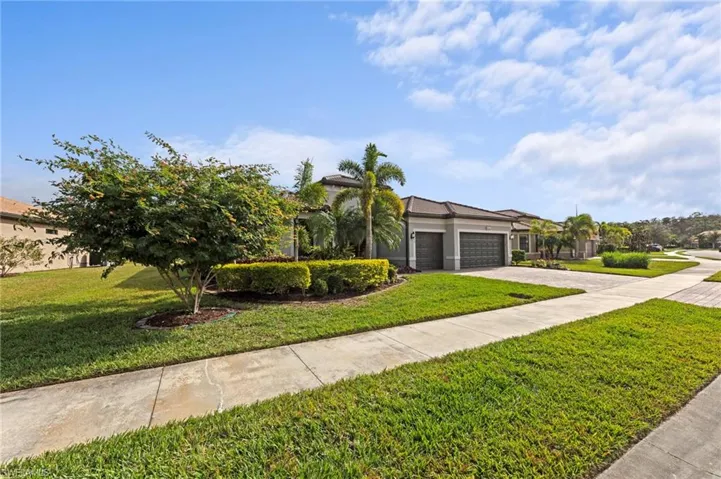 View of front facade featuring a front yard, decorative driveway, an attached garage, and stucco siding