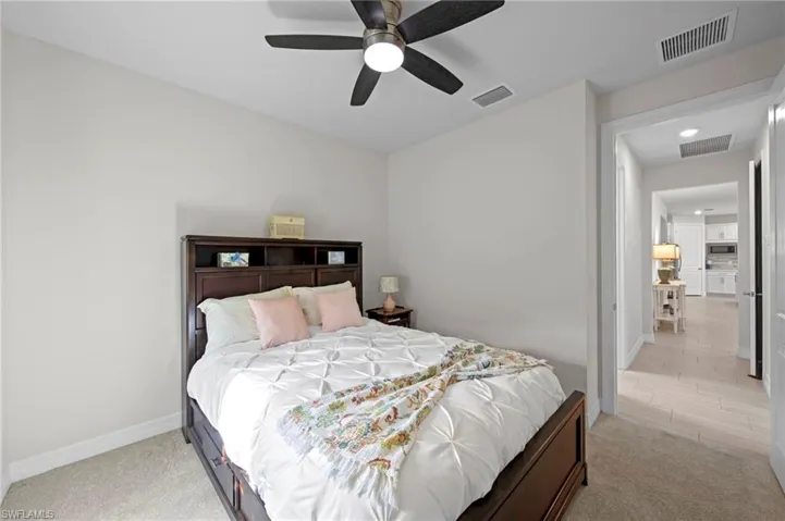 Bedroom with light colored carpet and a ceiling fan