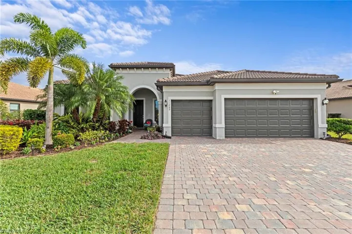 Mediterranean / spanish-style home with stucco siding, decorative driveway, an attached garage, a tiled roof, and a front yard