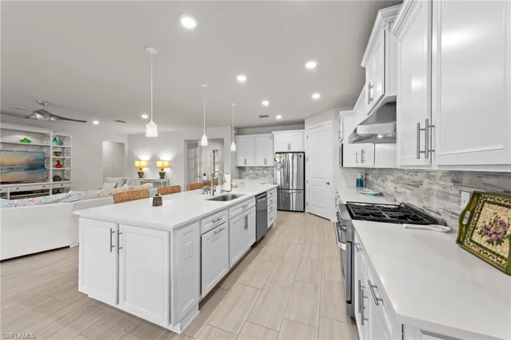 Kitchen with hanging light fixtures, open floor plan, white cabinets, appliances with stainless steel finishes, and recessed lighting