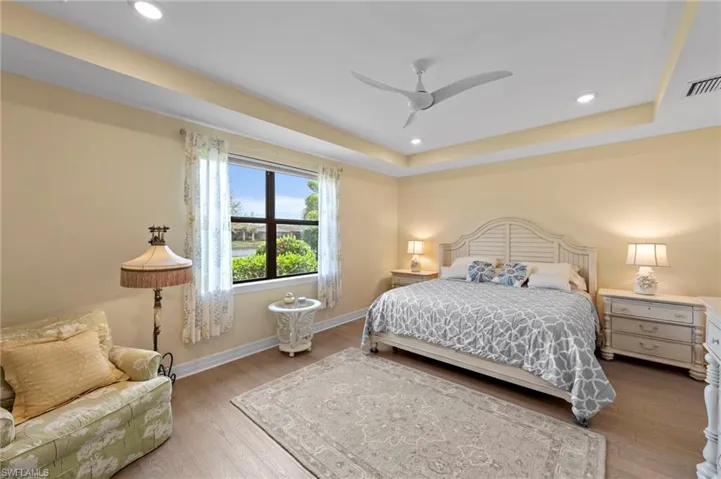 Bedroom with wood finished floors, recessed lighting, a ceiling fan, and a raised ceiling