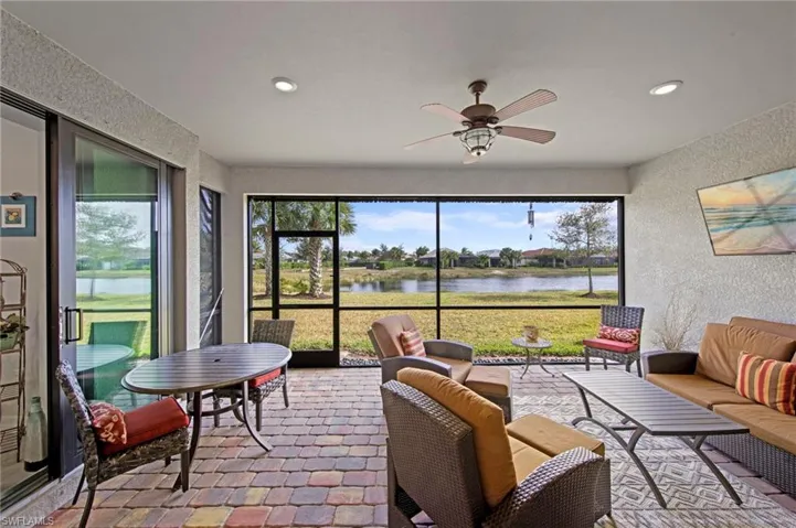 Sunroom / solarium featuring a water view, a textured wall, recessed lighting, and plenty of natural light