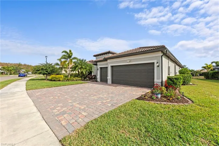 View of side of property with a garage, stucco siding, a yard, and decorative driveway