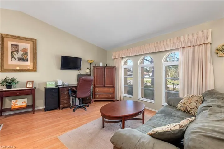 Living room with vaulted ceiling and light hardwood / wood-style flooring