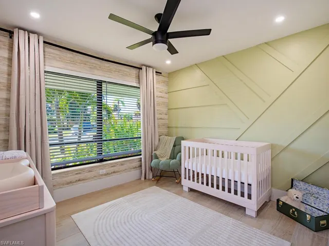 Bedroom with a crib, wood-plank tile finished floors, a ceiling fan, custom accent wall and wall coverings, and recessed lighting