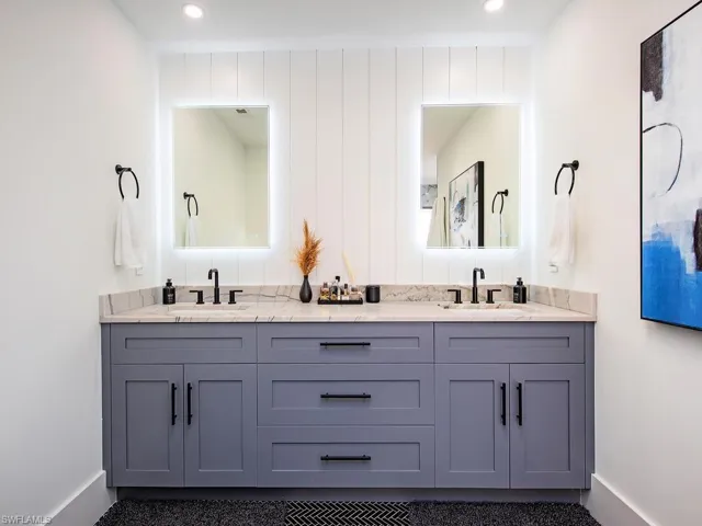 Bathroom featuring double vanity, ship lap accent wall, lit mirrors and recessed lighting