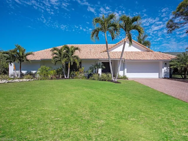 View of front facade featuring stucco siding, a garage, and a nicely landscaped front yard