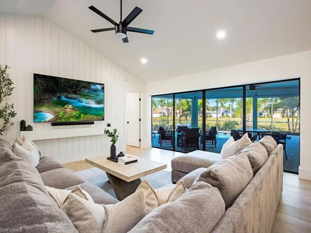 Living area with light wood-plank tile floors, a ceiling fan, lofted ceiling, ship lap accent wall, and recessed lighting