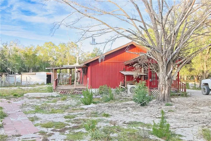 View of side of home with a wooden deck and an ac unit