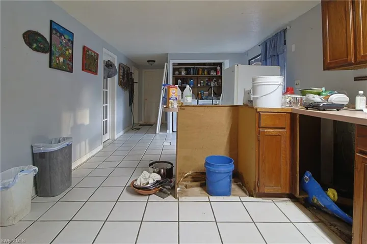 Kitchen with wood finish cabinets, freestanding refrigerator, light countertops, and light tile patterned floors