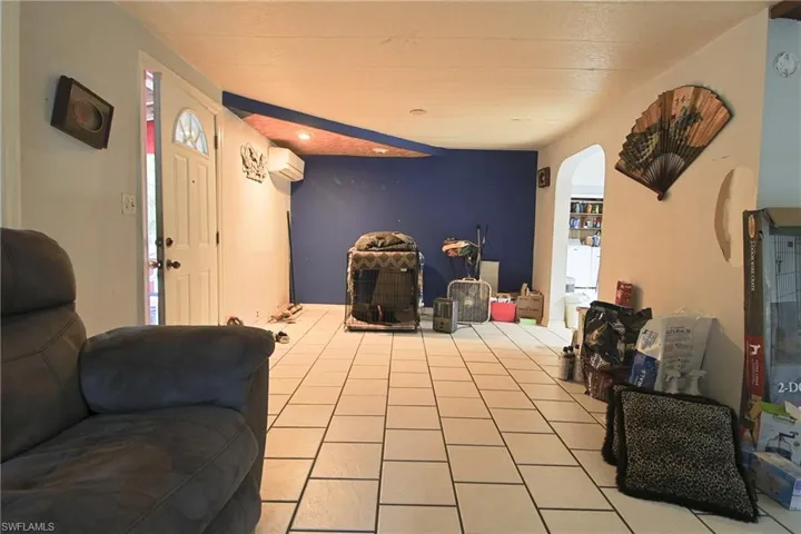 Tiled living area featuring arched walkways, a mini split for heating / cooling, and recessed lighting
