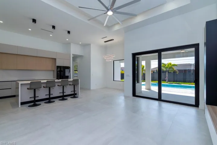 Unfurnished living room with a towering ceiling, recessed lighting, concrete floors, and a ceiling fan
