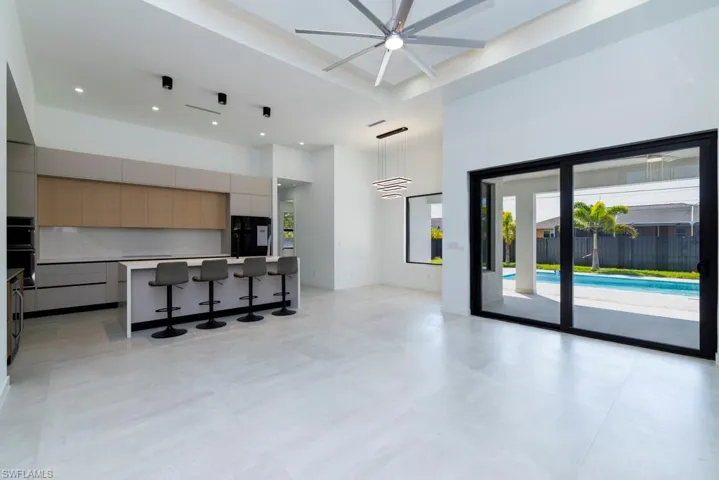 Unfurnished living room with a towering ceiling, finished concrete floors, french doors, recessed lighting, and beverage cooler