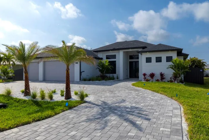 View of front of property with a front lawn, decorative driveway, stucco siding, and an attached garage