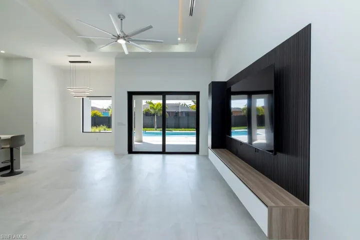 Unfurnished living room featuring a ceiling fan, recessed lighting, and a high ceiling