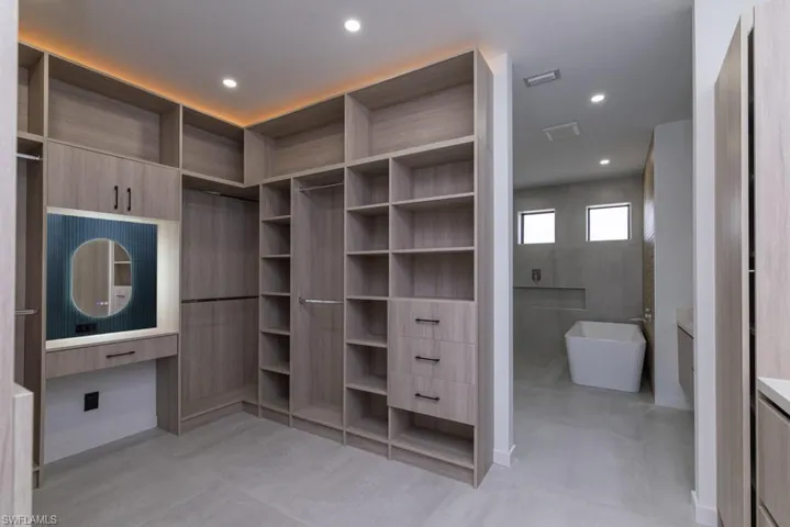 Kitchen featuring modern cabinets, an island with sink, open shelves, glass insert cabinets, and light stone counters
