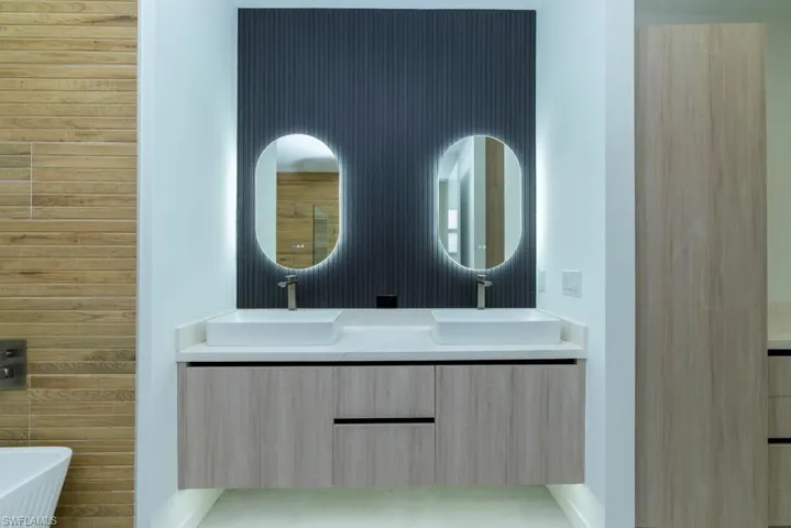 Bathroom featuring double vanity, a walk in shower, a freestanding bath, recessed lighting, and wood walls