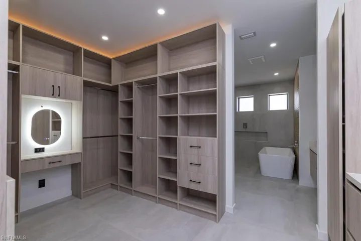 Kitchen with modern cabinets, black appliances, light stone counters, decorative light fixtures, and recessed lighting