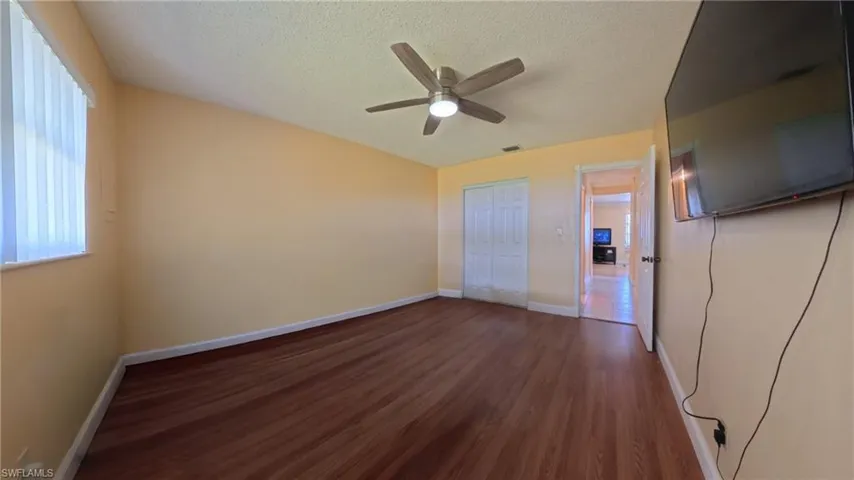 Unfurnished bedroom featuring dark wood finished floors, a textured ceiling, ceiling fan, and a closet
