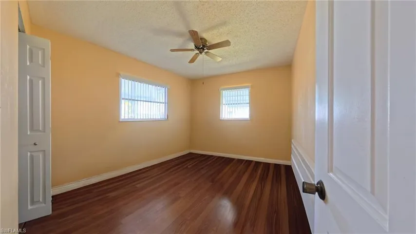 Spare room featuring dark wood-style flooring, a textured ceiling, and ceiling fan
