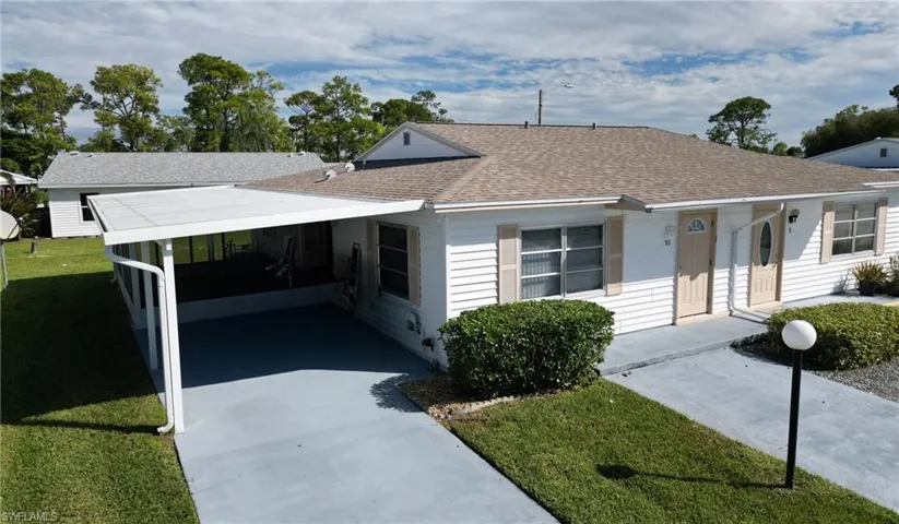 View of front of house featuring a shingled roof, a front lawn, concrete driveway, a carport, and crawl space