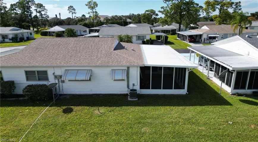 Back of house featuring a residential view, a yard, roof with shingles, and a sunroom
