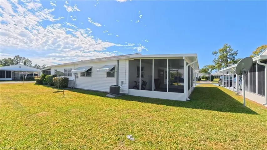 Rear view of house featuring a lawn and a sunroom