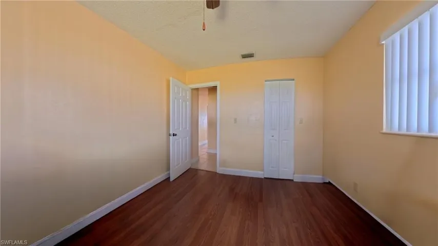 Unfurnished bedroom with dark wood-style flooring, a textured ceiling, a closet, and a ceiling fan