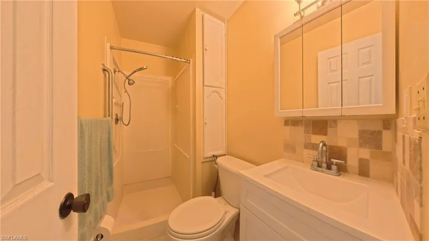 Bathroom featuring backsplash, vanity, and a shower stall
